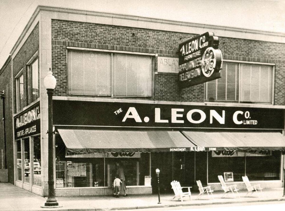 The original A. Leon Company store in Welland, Ontario — A brick corner building with striped awnings and The A. Leon Co. Limited sign.